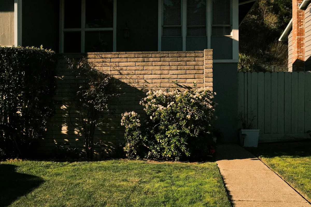 Plain concrete path running beside a lawn to the front of a house